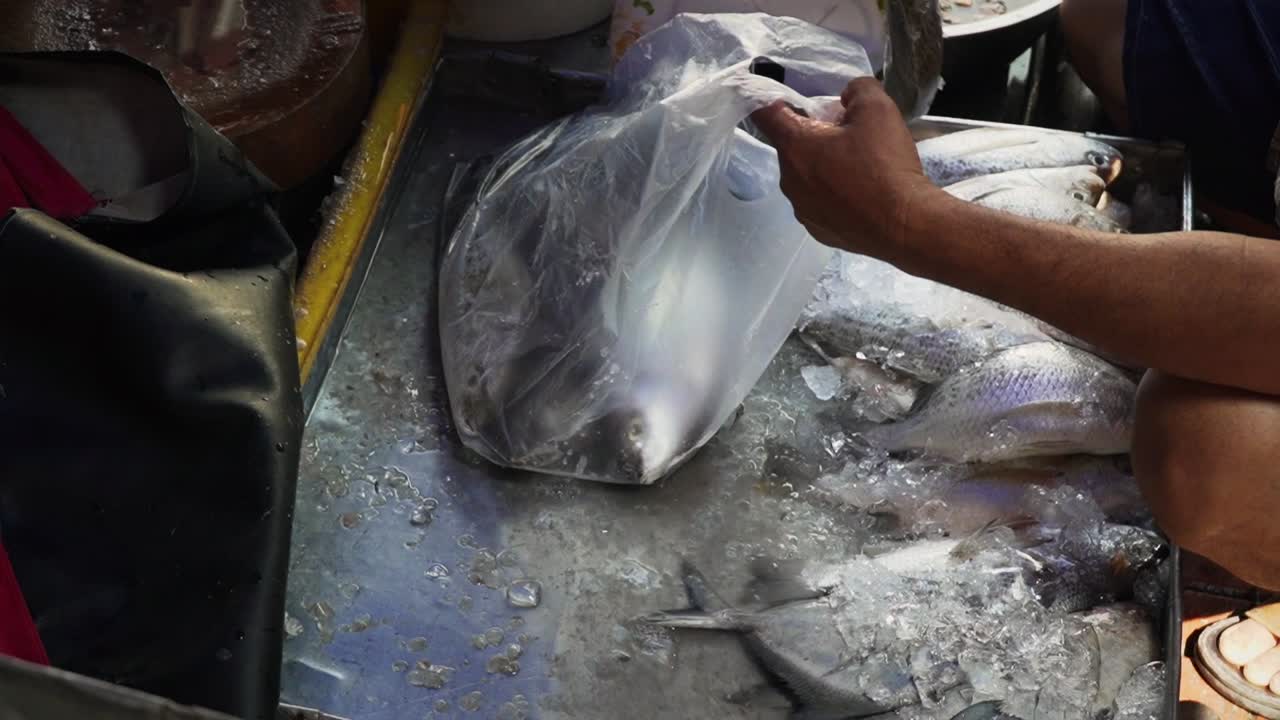 Freshly caught fish being bagged and transported at market in asia ...