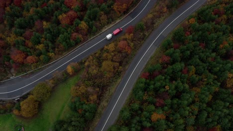 Top-down-View-Of-Cars-Driving-On-Curve-Road-Through-Forest-With-Autumnal-Trees