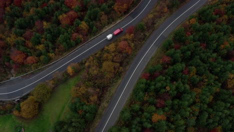 Vista-De-Arriba-Hacia-Abajo-De-Los-Automóviles-Que-Circulan-Por-Una-Carretera-Curva-A-Través-Del-Bosque-Con-árboles-Otoñales