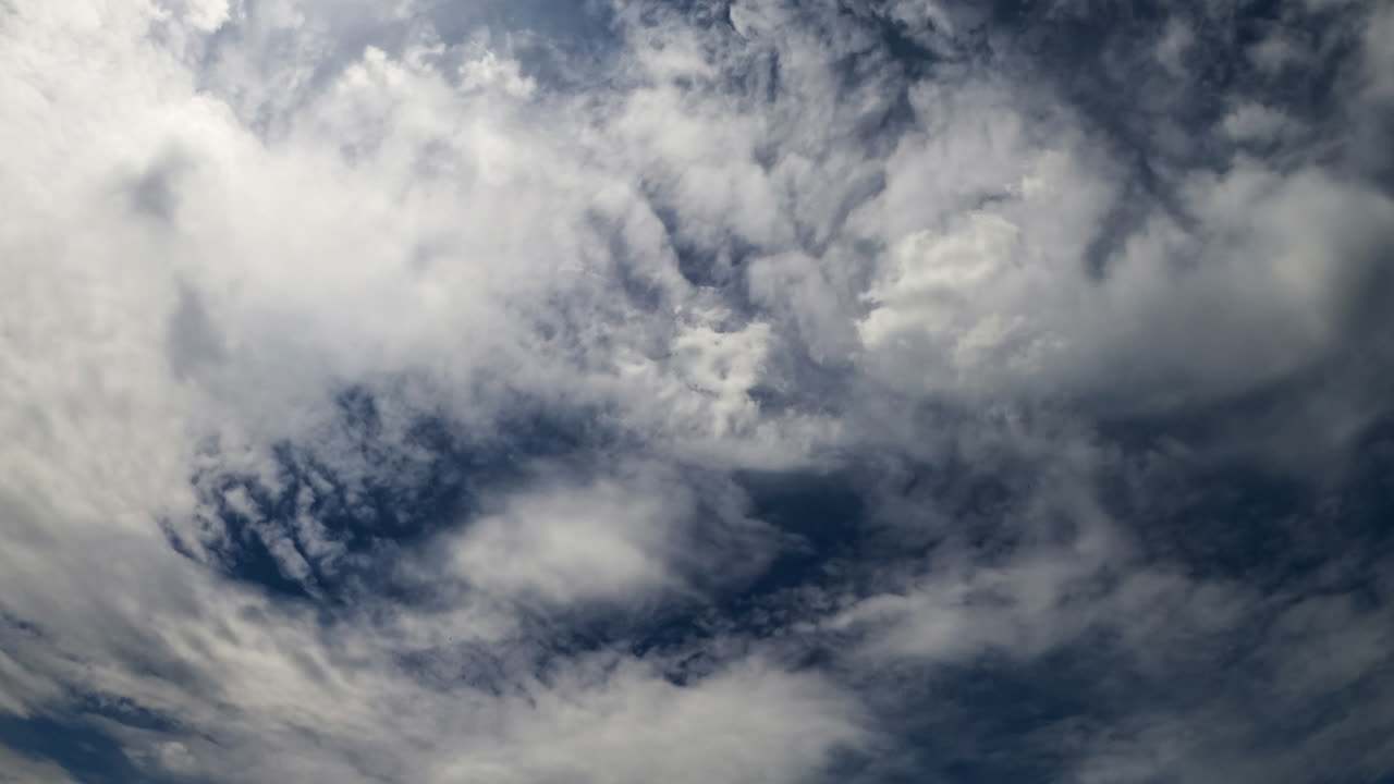 Stratus clouds covering the deep blue sky. Low angle view at the cloudscape spreading by the atmosphere. Timelapse.