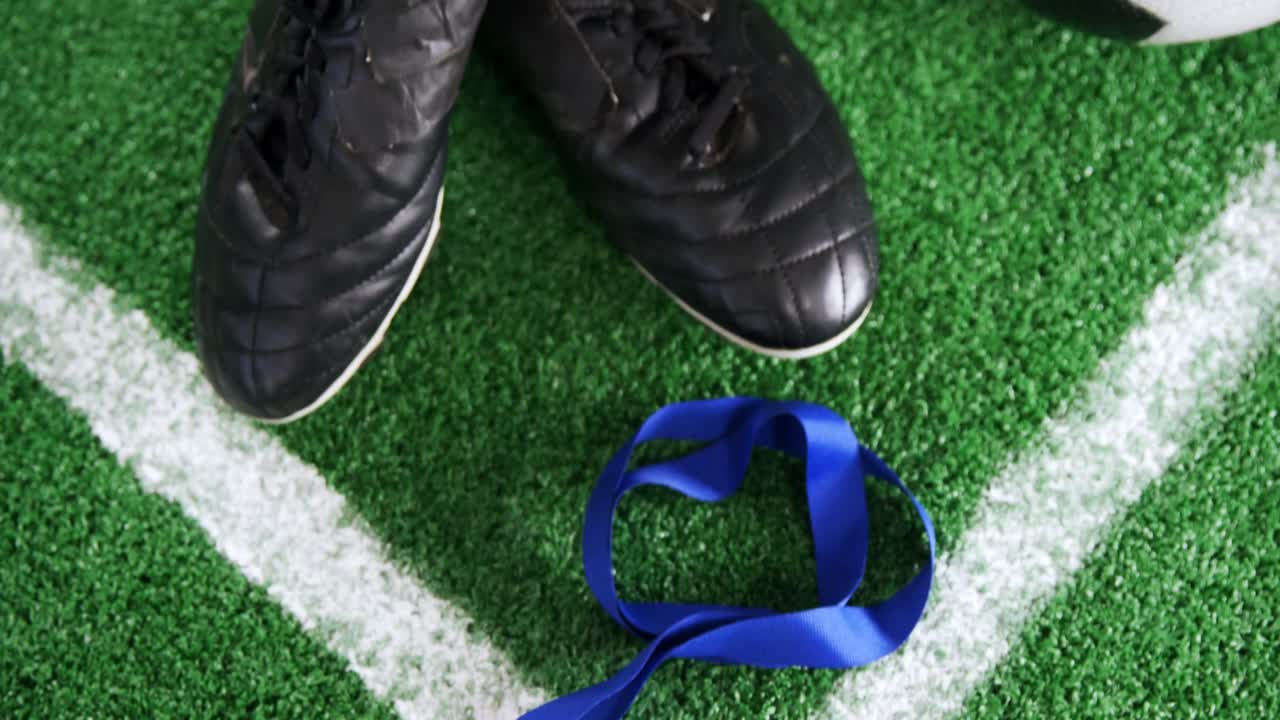 Pallone da calcio, medaglia e tacchetti su erba artificiale 4k