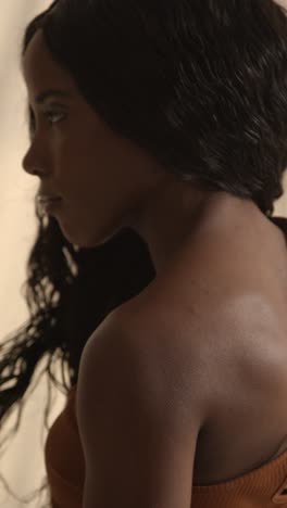 studio beauty shot of young woman with long hair against neutral background viewed in profile