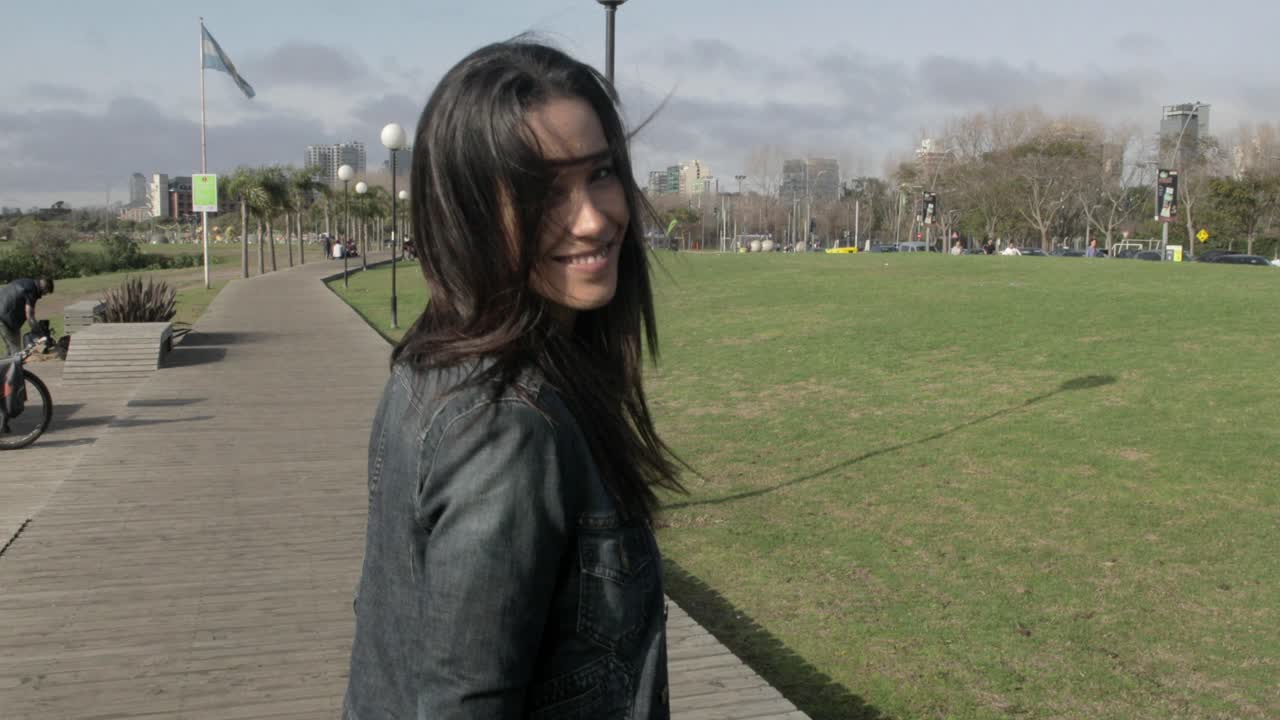 Giovane donna che cammina e sorride in un parco urbano