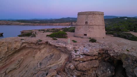 barefoot hippie girl practicing yoga at sunset near torre des carregador, ibiza, spain. majestic aerial view flight drone shot footage from above