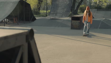 young skater girl turning on a ramp at sunset in a skate park