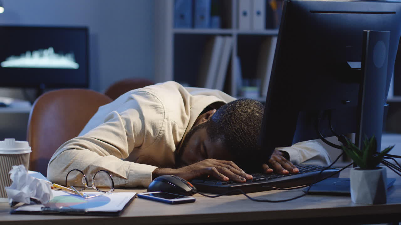 Office Worker Sleeping On The Table In Front Of The Computer In The Office At Night