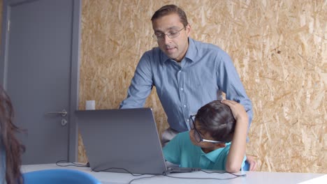 Computer-science-teacher-explaining-task-to-schoolboy