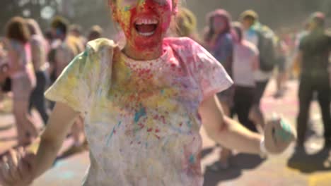 young happy girl in colourful powder is jumping and screaming on holi festival in daytime in summer, color concept