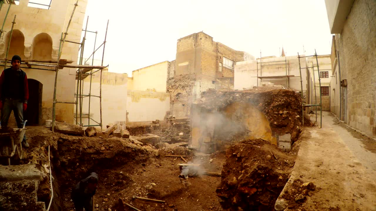 Operai edili al lavoro in una fossa di fondazione nel centro storico di Urfa. Resti di rovine sotto terra.