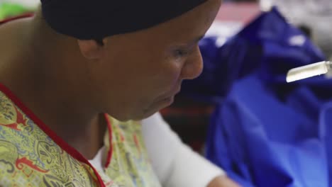 Mixed-race-woman-using-sewing-machine-in-factory