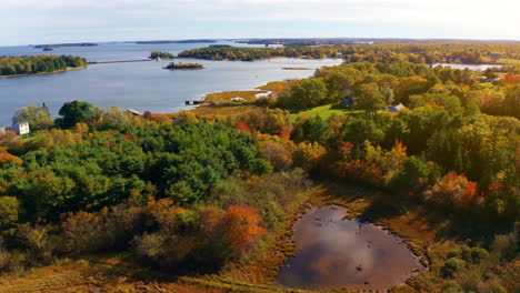 aerial drone shot over the coastline of oak island, nova scotia, canada.
high view of the sea, autumn colorful trees foliage. picturesque landscape. fall vibrant colors.