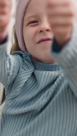 cheerful little girl shows thumb up gestures sitting in wheelchair on blurred background. schoolgirl with disability smiles looking in camera closeup