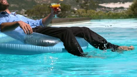 Businessman-sitting-on-buoy-while-drinking-cocktail