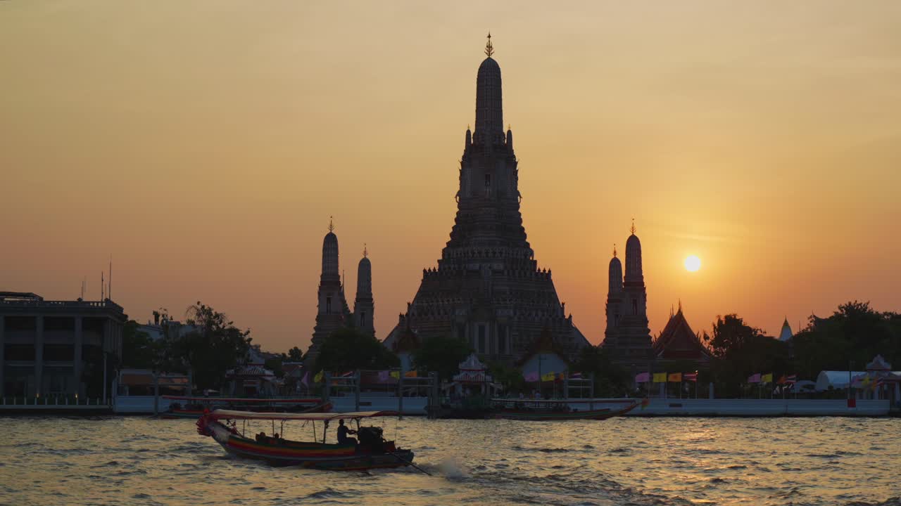 una vista hipnótica del impresionante templo de wat arun del amanecer en bangkok, tailandia durante una impresionante puesta de sol, con un barco tradicional de cola larga flotando en el río sereno