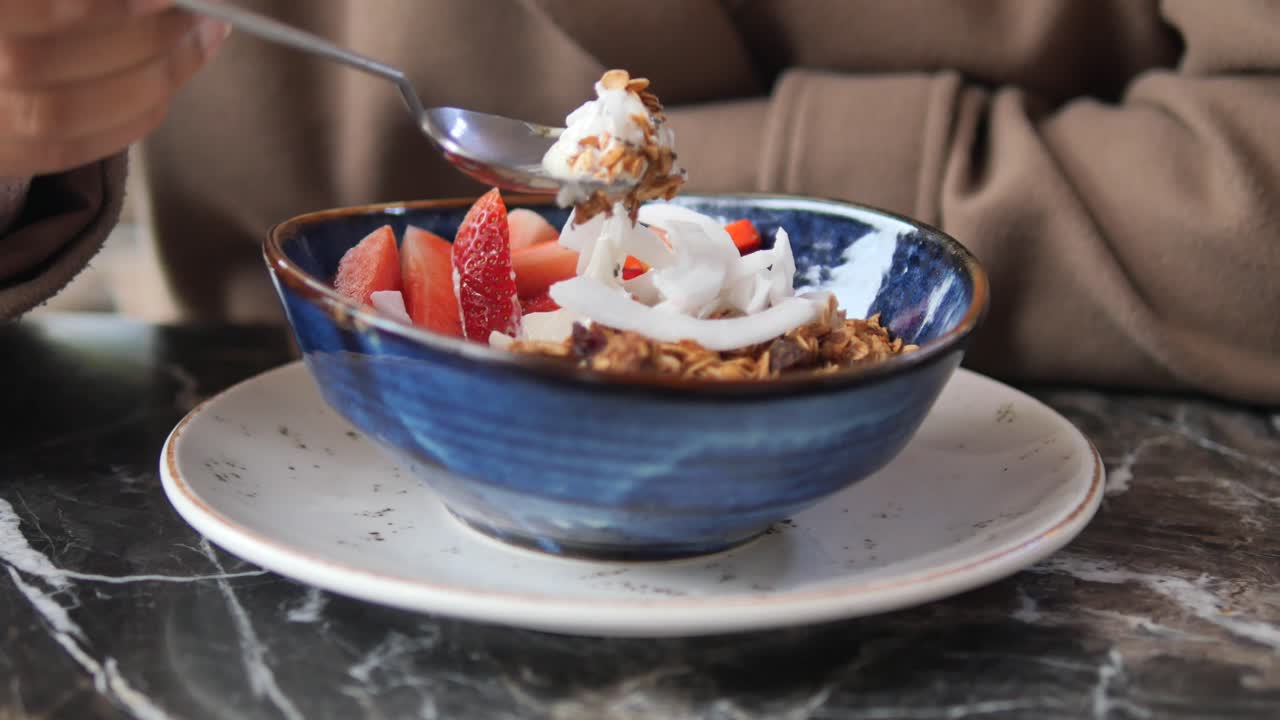 Close-up of a Person Eating Healthy Granola with Strawberries and Coconut