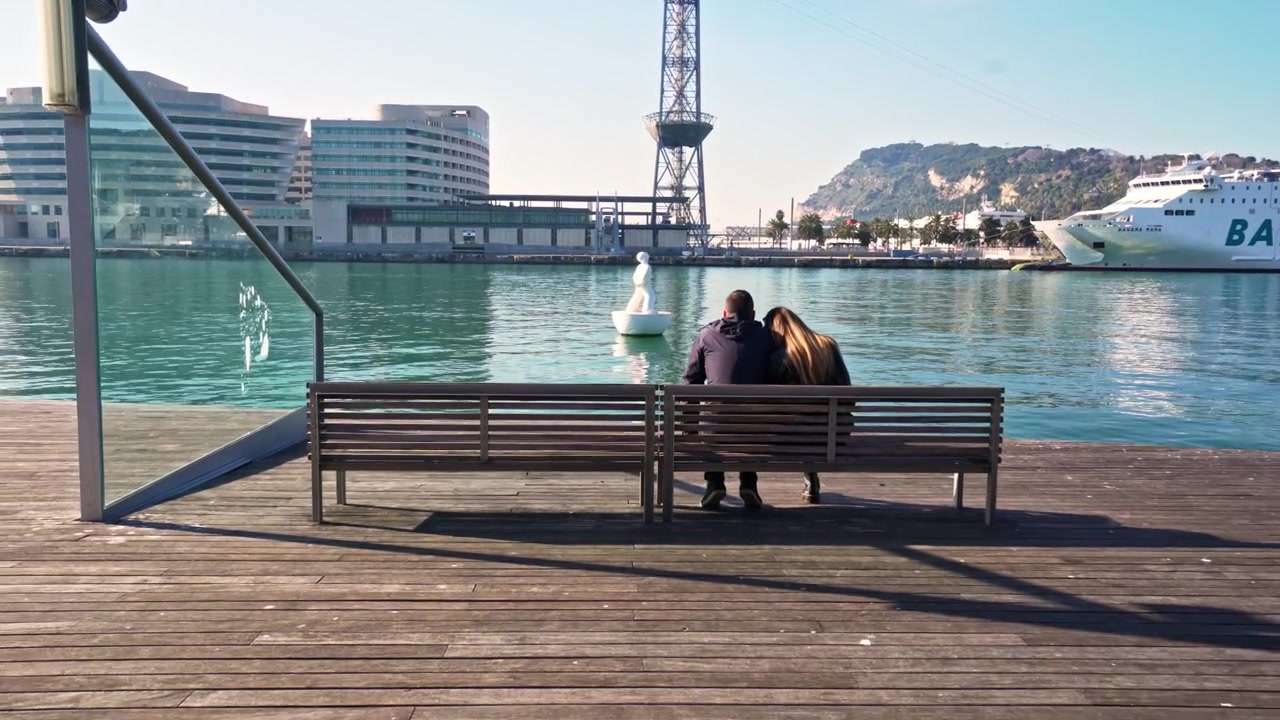 Pari istuu penkillä ja katsoo satamaan Barcelonassa, Espanjassa