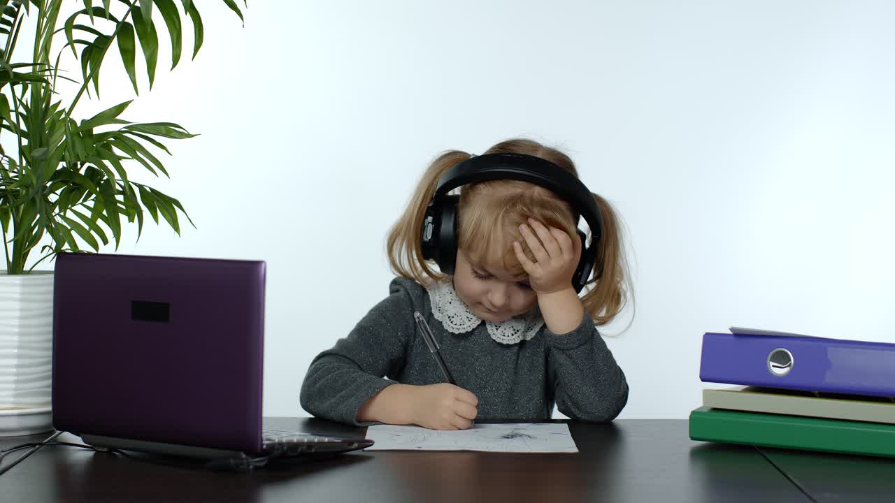 Bambina in età prescolare che segue lezioni online a distanza da casa. Bambina che studia usando un computer portatile digitale.