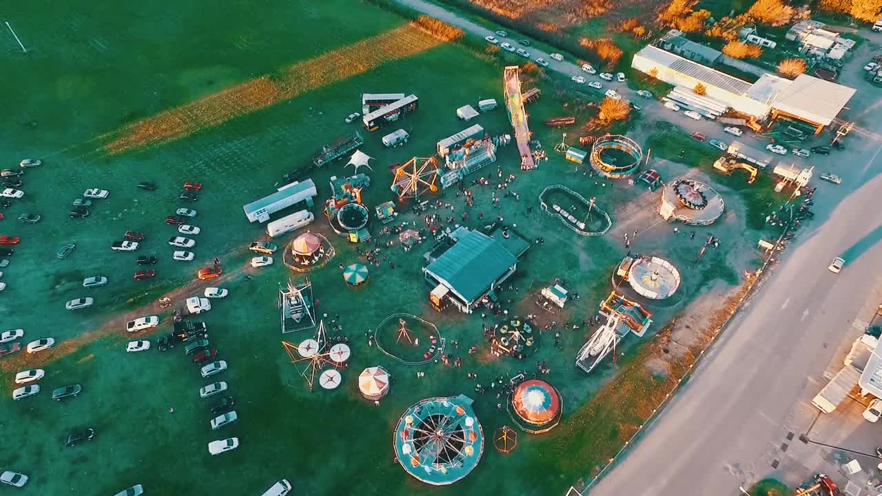 Aerial drone footage of a carnival in small town in the sunset with sun rays drawing in the floor