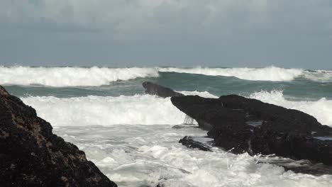 massive ocean waves rolling toward shore. waves crashing into large rocks. cresmina beach (praia da cresmina), portugal.