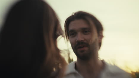 man talking to a woman in a golden hour field