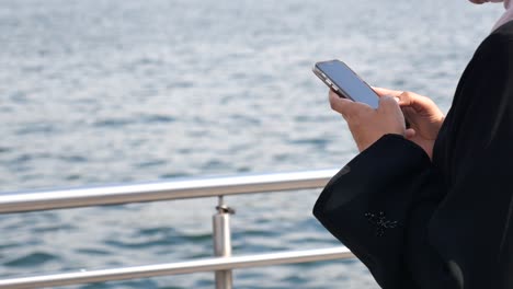 woman using phone by the water