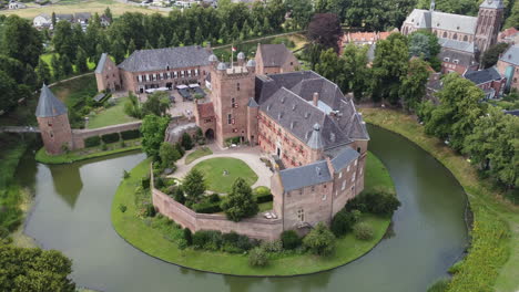 kasteel-huis-bergh,-the-netherlands:-aerial-view-traveling-in-the-beautiful-castle-and-appreciating-the-moat,-the-towers-and-the-nearby-church