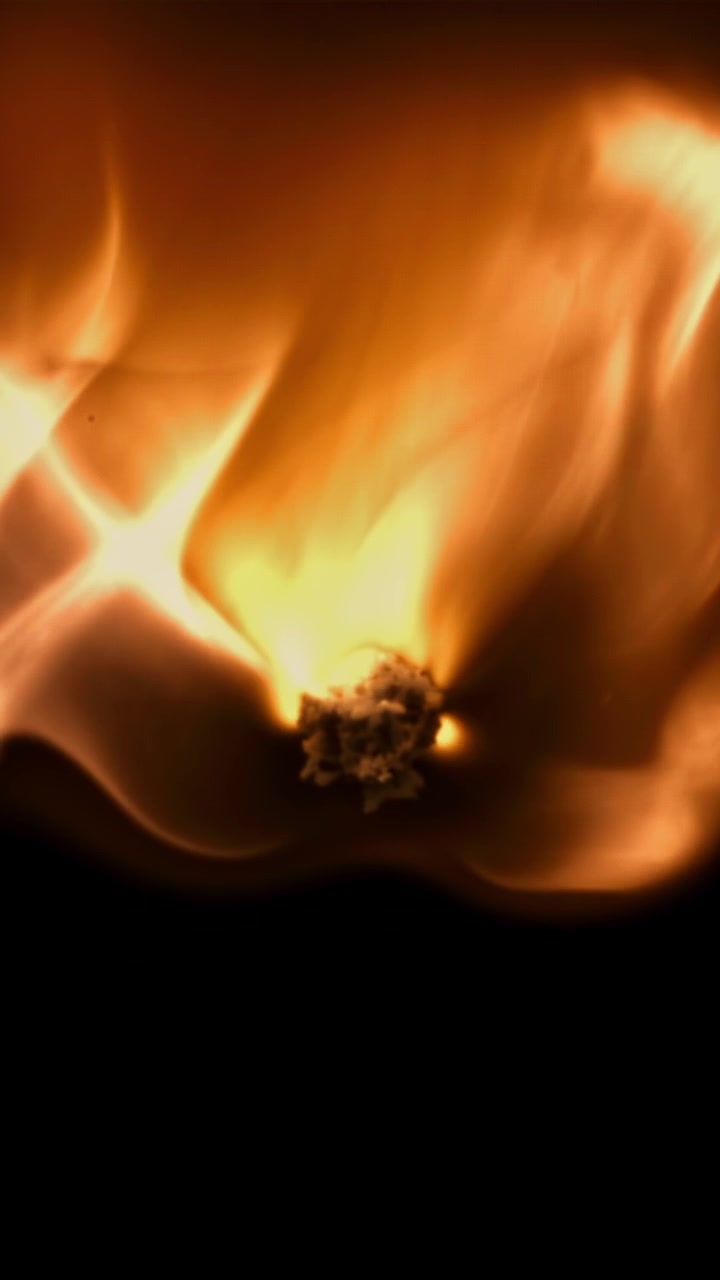 Primer plano en cámara lenta de una llama encendiéndose y ardiendo sobre negro