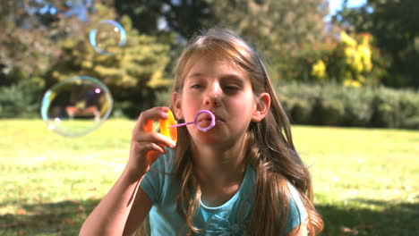 smiling young girl blowing into a bubble wand