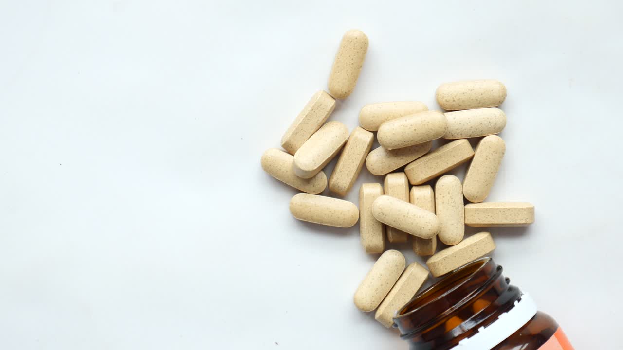 cápsula de medicina herbal que cae sobre el blanco