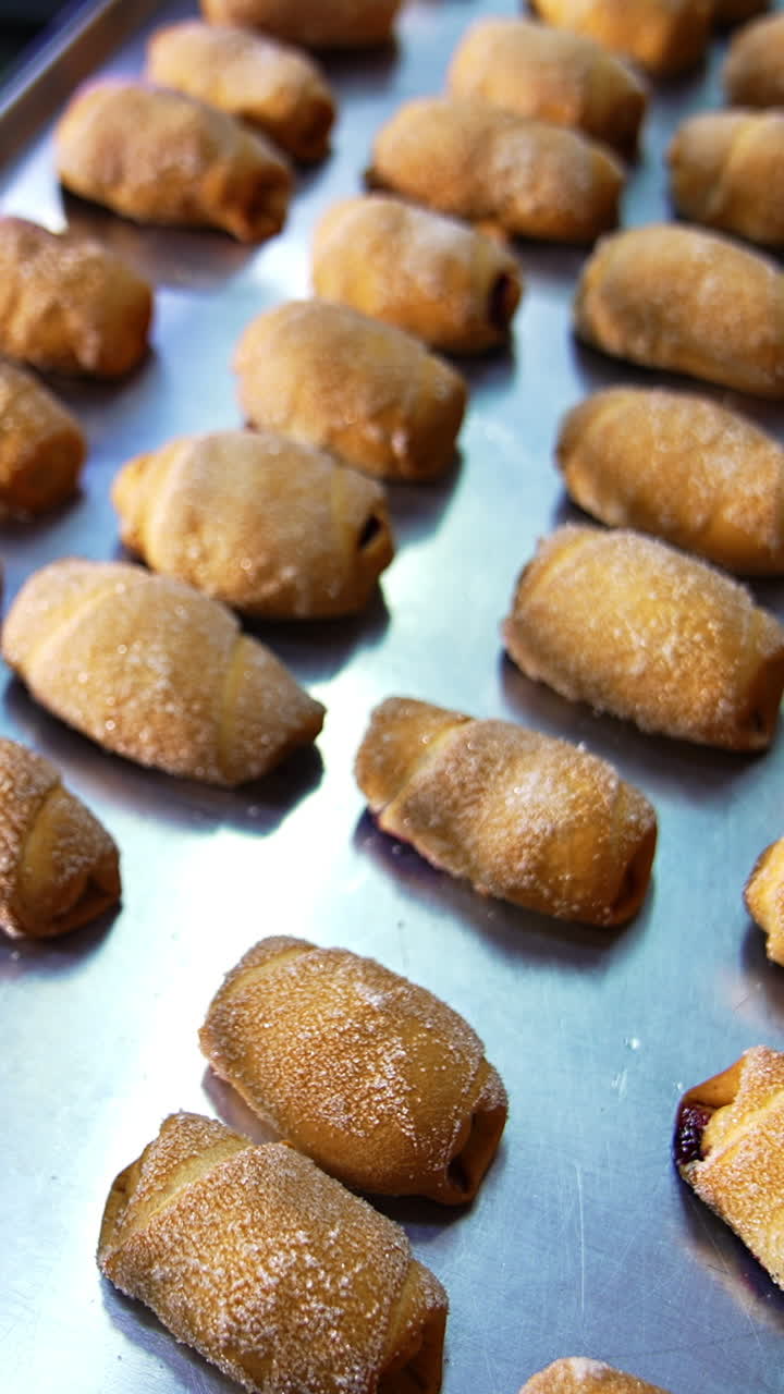 Delicious fresh well- baked pastry put on baking sheets. Sweet desserts manufacturing at bakery. Close up. Vertical video