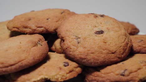 Vista-Lateral,-Montón-De-Galletas-Con-Trocitos-De-Chocolate-Giran-Sobre-Fondo-Blanco,-Primer-Plano