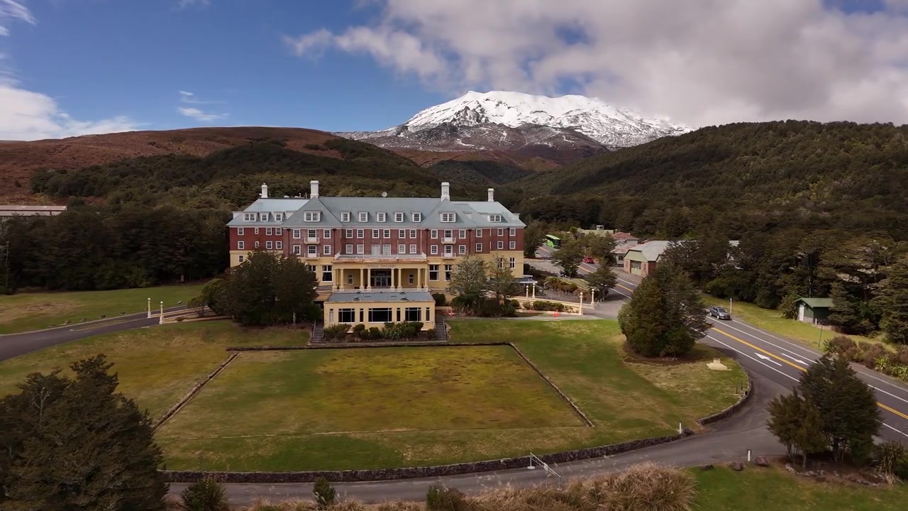 Laterale drone-volgopname van het Chateau Tongariro Historisch Hotel in het Mount Tongariro-gebied, Nieuw-Zeeland. 4K 60fps beelden van de erfgoedarchitectuur en het alpenlandschap.