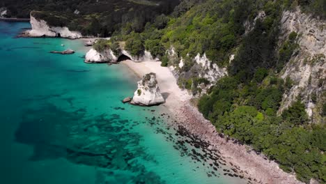 cathedral cove y te hoho rock vuelan desde el aire hacia atrás revelando la toma, el paisaje costero en un día parcialmente nublado en un popular lugar turístico