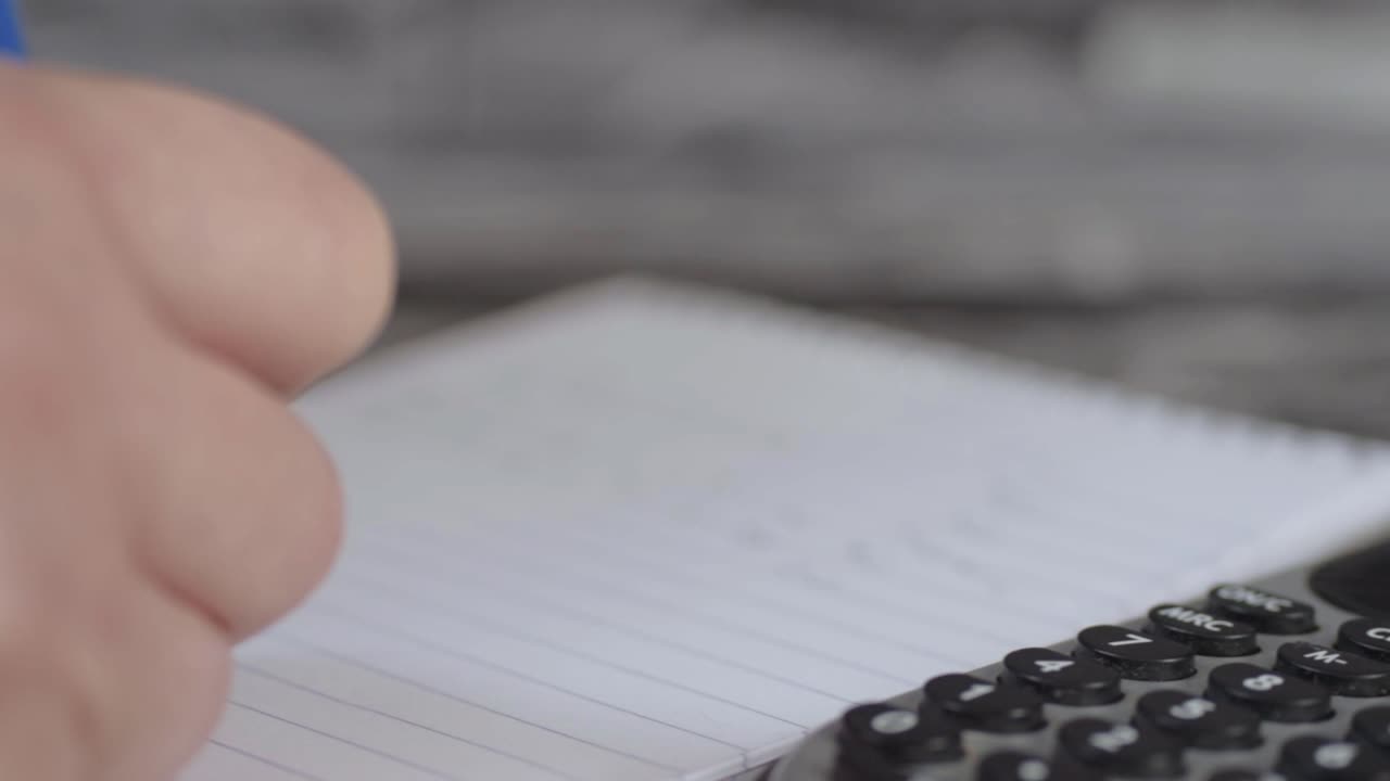 Hand writing with calculator close up panning shot