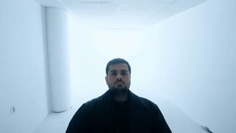 hombre con una chaqueta negra posando en un estudio blanco