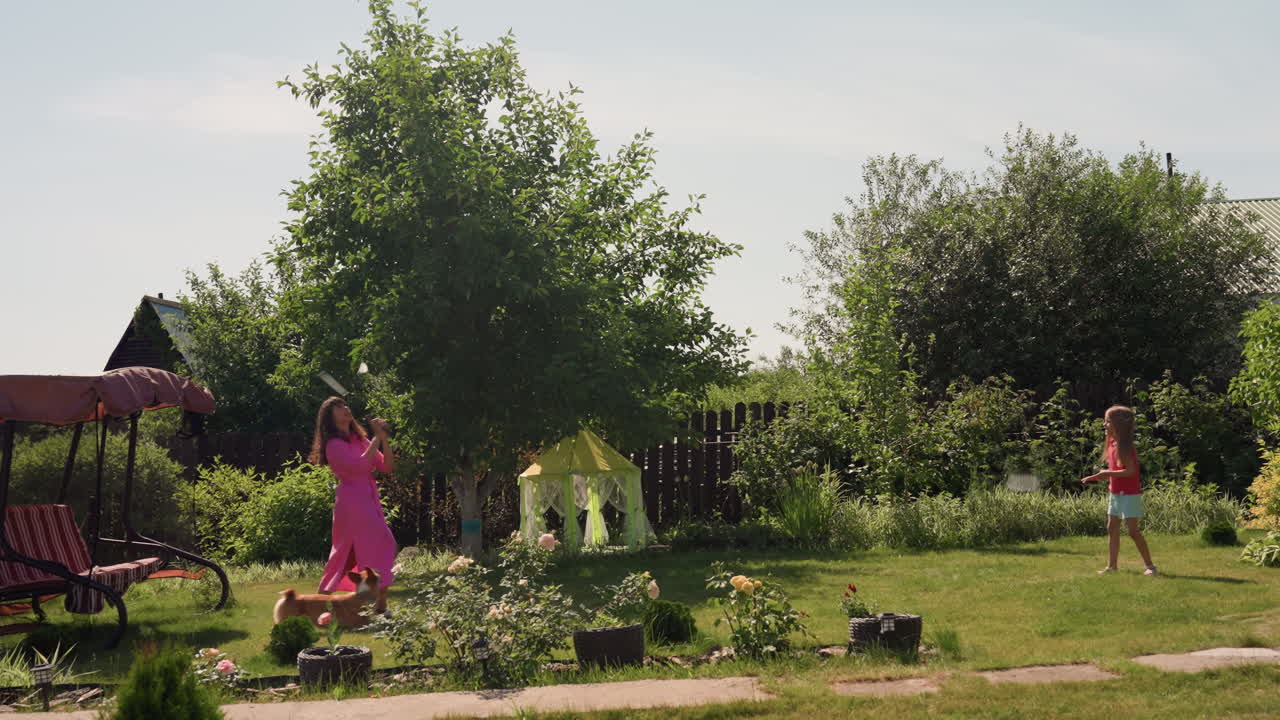 White Mother And Daughter Strolling Past Swing And Shaded Canopy, Relaxed Backyard Afternoon With Lawn Chairs And Tidy Flowerbeds, Calm Domestic Escape With Soft Sunlight, Slow Pace And Family