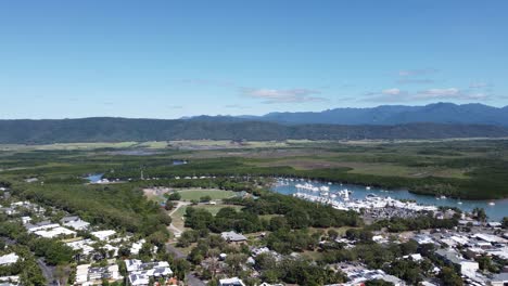 4k aerial view of a small coastal town with a boat harbour in north queensland, australia