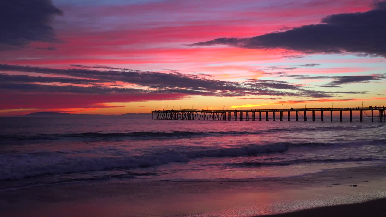 una hermosa costa roja anaranjada al atardecer tomada a lo largo de la costa central de california con el muelle de ventura distante 2