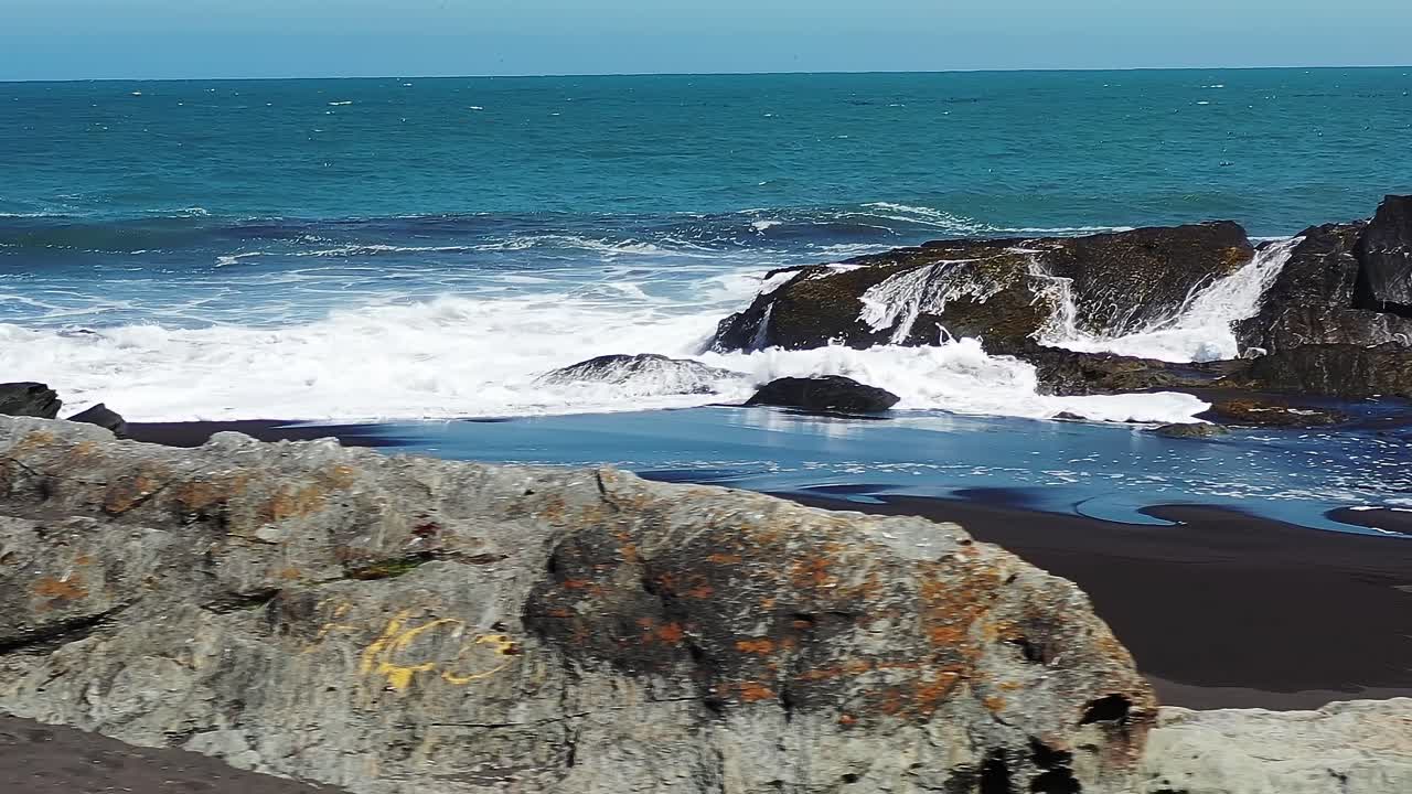 Le onde si infrangono sulle rocce lungo la costa del Cile durante il giorno.