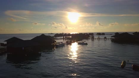 Aerial-flight-towards-stunning-sunset-over-a-beach-resort-in-Mabul,-Malaysia