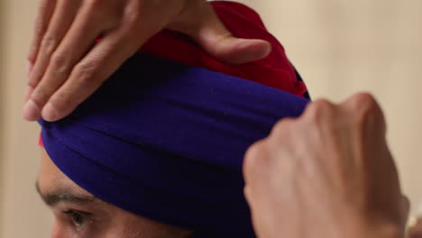 toma de estudio de cerca de dos hombres sikh atando tela para turbante contra un fondo plano 1