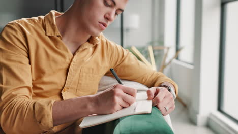 man writing in notebook