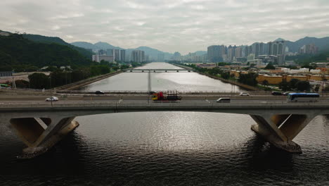 aerial drone shot cars driving on highway over a wide waterway bridge, hong kong