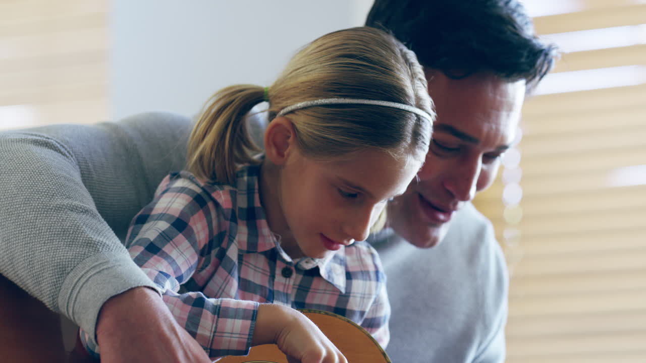 padre e hija aprendiendo a tocar la guitarra juntos