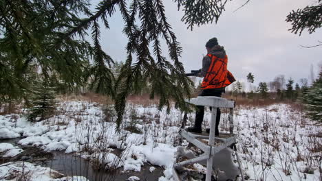 Wildlife-hunter-at-a-watch-tower,-waiting-for-prey,-in-a-snowy-forest,-winter-day