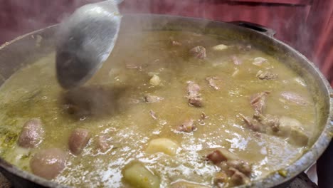 cooking a hearty stew in a large pot outdoors