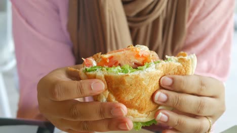 una mujer comiendo un sándwich.