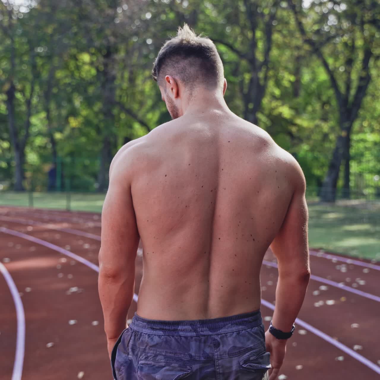 . Handsome man at the stadium. Rear view of naked sportsman at stadium