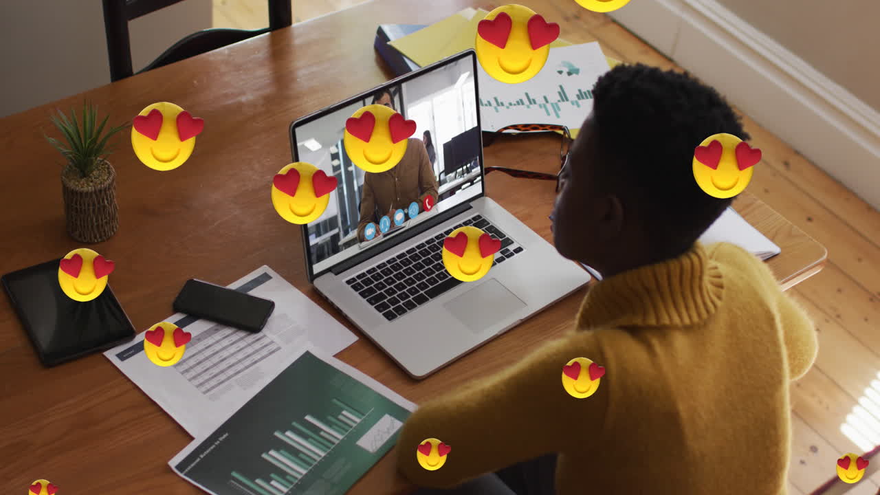 Animation of heart eyes face emojis over african american woman having video call on laptop