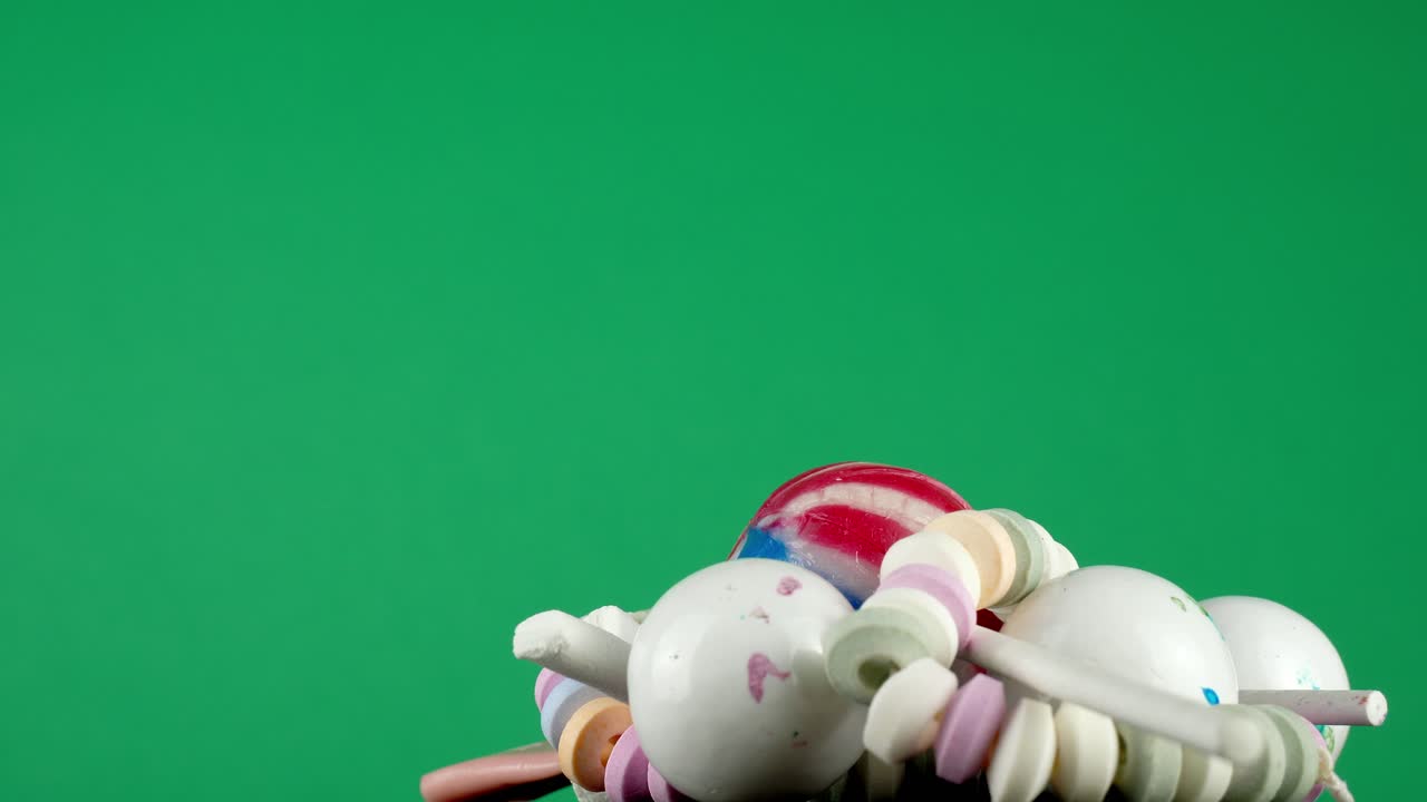 Una porzione di gustose caramelle assortite, che ruota su un vassoio su uno sfondo da studio verde intenso.
